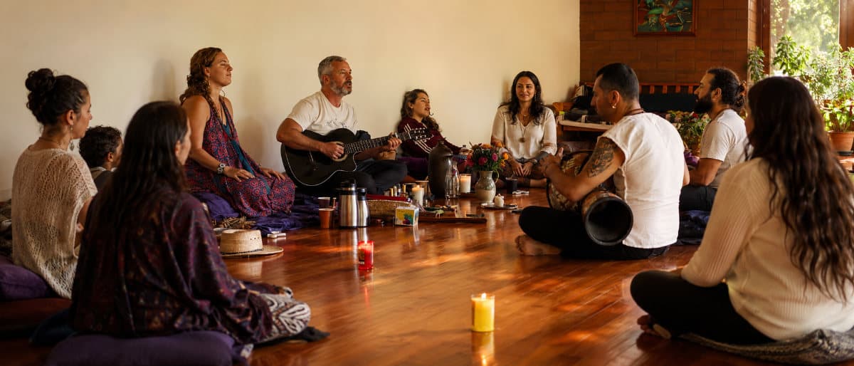 A group seated in a ceremonial circle with candles and live music